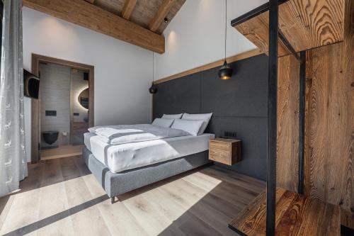 a bedroom with a large bed and a wooden wall at Kellnergut Luxus-Chalet "FRIEDA" in Mühlbach am Hochkönig