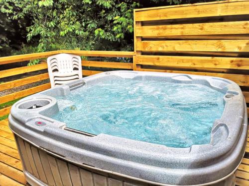 a hot tub sitting on a deck with a chair at Kingfisher Lodge-HuntersMoon -Warminster-Longleat-Bath in Warminster