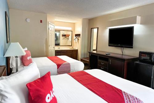 a hotel room with two beds and a flat screen tv at Bonita Lakes Inn by Capital O Meridian I20 in Meridian