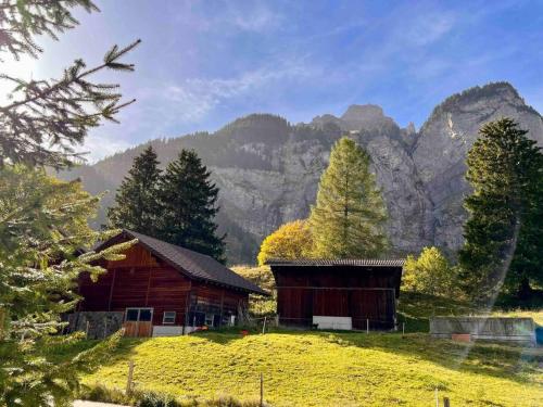 a barn on a field with mountains in the background at Wesley House in Kandersteg