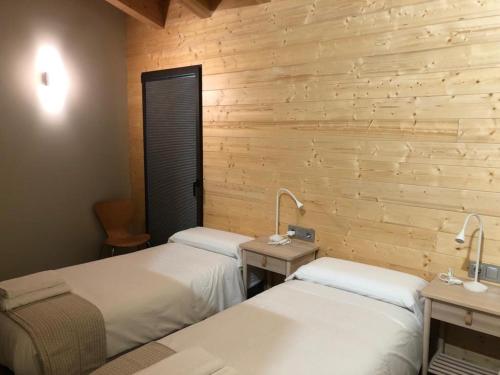two beds in a room with wooden walls at Cal Mureu in Pardines
