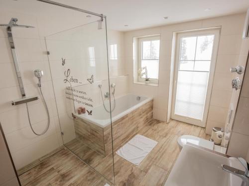 a bathroom with a shower and a tub and a sink at Landhaus Harmonie in Riezlern