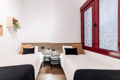 twee bedden in een kamer met een raam bij AlohaMundi Campana II in Sevilla