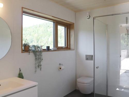 uma casa de banho com um chuveiro, um WC e uma janela. em Holiday home Søndeled em Søndeled