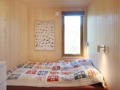 um quarto com uma colcha numa cama com uma janela em Holiday home Søndeled em Søndeled