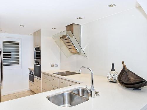a white kitchen with a sink and a stove at The Breakers, Apartment 4 in Noosa Heads