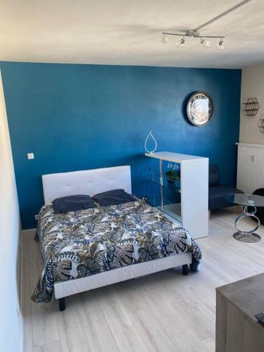 een slaapkamer met een bed met een blauwe muur bij Appartement tout confort in Limoges