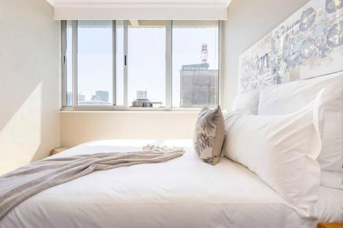 un letto bianco con cuscini bianchi e una finestra di Perspectives on Roeland a Città del Capo