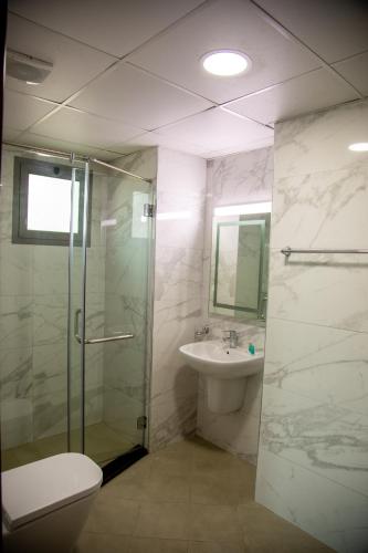 a bathroom with a shower and a toilet and a sink at The Apple Residence in Juffair