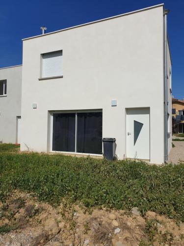 ein weißes Haus mit zwei Fenstern und einem Hof in der Unterkunft MAISON A in Saint-Jean-de-Thurigneux