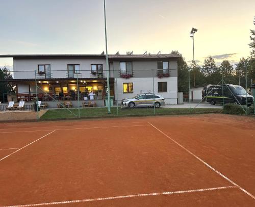 una pista de tenis con un coche aparcado frente a un edificio en Raketa Residence, hotel & restaurant en Brezany