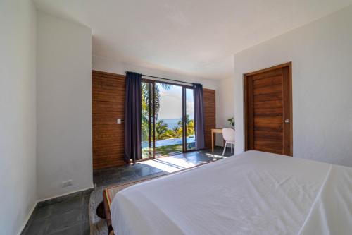 Un dormitorio con una cama blanca y una ventana grande. en Hacienda Cocuyo, en Monte Rojo