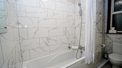 a white bathroom with a tub and a toilet at Cozy 2 bed Apt with Private Garden in London