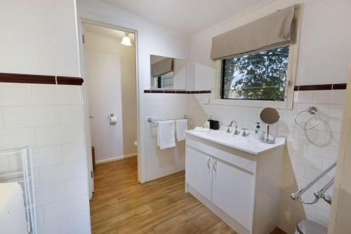 a white bathroom with a sink and a mirror at Katisha Cottage in Paynesville