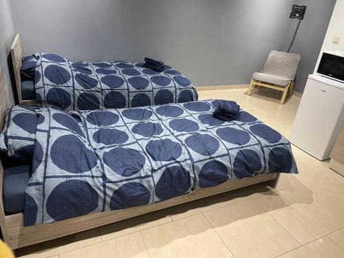 a bed with a blue and white comforter and a chair at Studio proche de l’aéroport/gare/centre ville in Charleroi