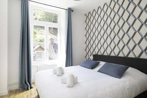 Un dormitorio con una cama blanca con almohadas azules y una ventana en Villa Pax 3 - La Bourboule - 6pers, en La Bourboule