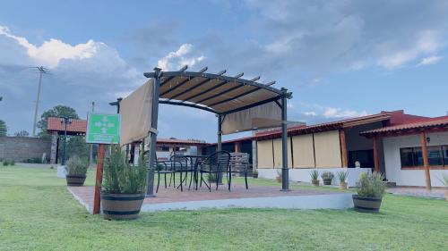 a pavilion with a table and chairs in front of a building at Finca Los Angeles Hospederia & Sociales in Huasca de Ocampo
