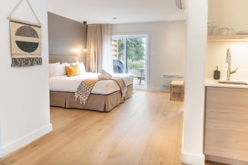 a bedroom with a large bed and a kitchen at Suites du Lac Moore in Mont-Tremblant