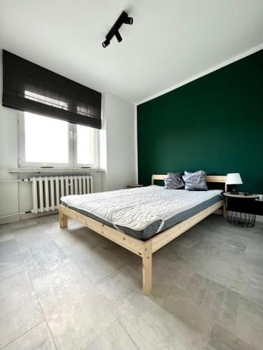 a bedroom with a bed with a green wall at Panorama Apartment Kraków in Krakow