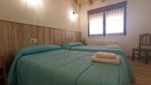 2 Betten in einem Zimmer mit grüner Bettwäsche und einem Fenster in der Unterkunft El Mirador de la LLeira in Ferreras de Arriba