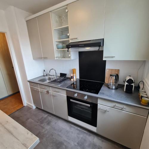 une cuisine avec des armoires blanches et un four à plaques de cuisson dans l'établissement La Madrague appartement front de mer, à Marseille