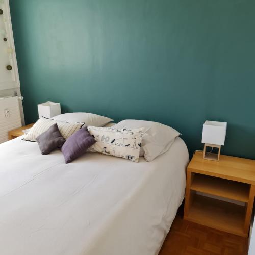 - un lit blanc avec des oreillers et un mur bleu dans l'établissement La Madrague appartement front de mer, à Marseille