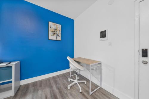 ein Büro mit einer blauen Wand, einem Schreibtisch und einem Stuhl in der Unterkunft Enchanting Studio in Little Havana in Miami