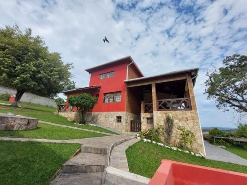 una casa roja con un avión volando sobre ella en Chácara guararema, en Guararema