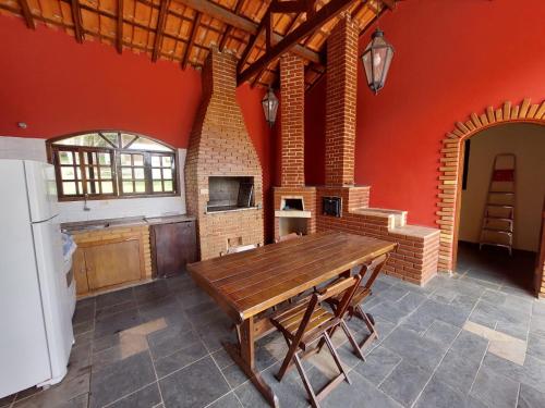 cocina con mesa de madera y chimenea en Chácara guararema, en Guararema