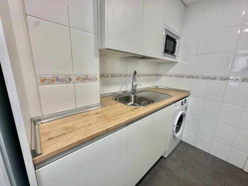 una pequeña cocina con fregadero y lavadora en La Ibiza del Pilar ComoTuCasa, en Zaragoza