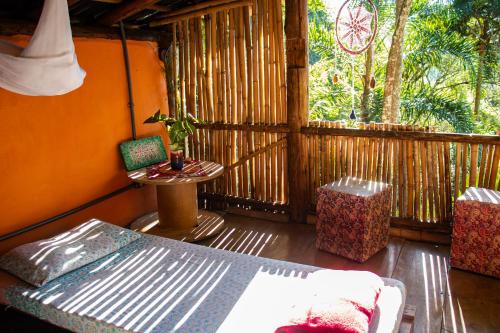 a room with a bed and a table on a porch at Remo Hostel in Parati-Mirim