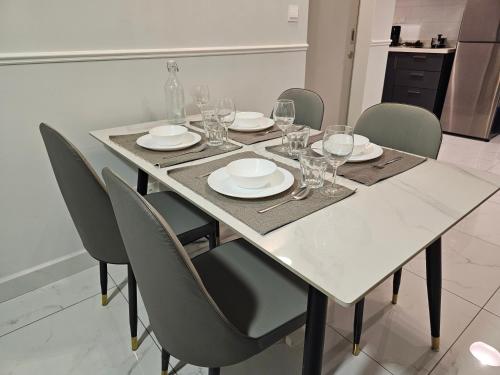 a white table with chairs and plates and wine glasses at Arte Cheras The Premium Suites by iLuxHome in Kuala Lumpur