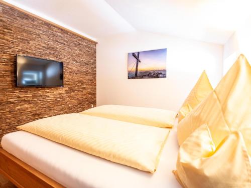 a bedroom with a bed and a tv on a brick wall at Landhaus Harmonie in Riezlern