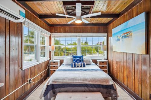 a bedroom with wooden walls and a bed with blue pillows at Beach House on the Sand in St Pete Beach