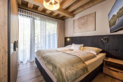 1 dormitorio con cama grande y ventana grande en Natur Zeit - Alpine Garden Apartments, en Mayrhofen