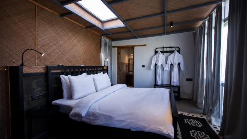 um quarto com uma cama com lençóis brancos e almofadas em The Merak em Meruk
