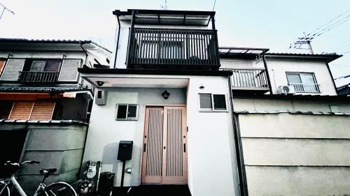 a white building with a red door and balconies on it at 花田屋HANADAYA in Kyoto