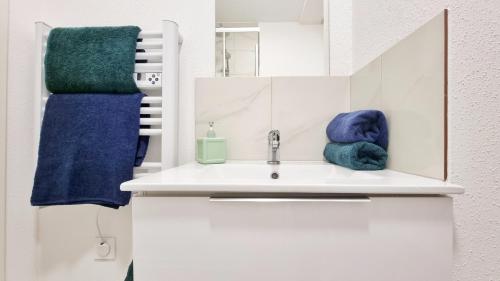 a bathroom with a sink with towels and a mirror at La Résidence Évasion 3 - Original - Gare - Wifi - Relax BNB in Mulhouse
