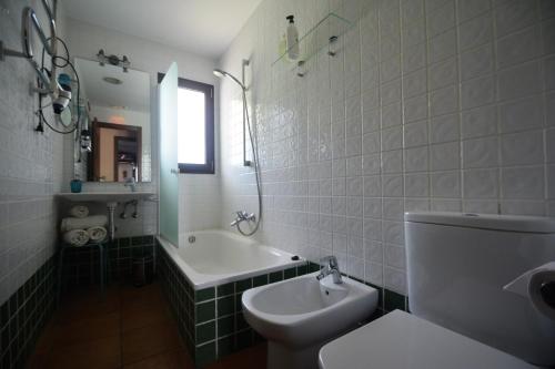 a bathroom with a toilet and a tub and a sink at Posada San Marcos in Alájar