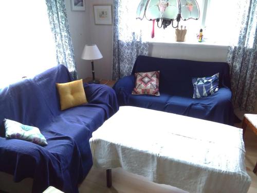 a living room with a blue couch and a table at Hus uthyres i natursköna Glava, Arvika in Glava