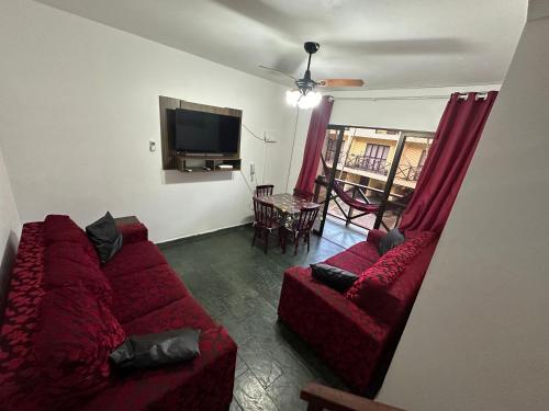 a living room with two red couches and a television at TRIPLEX piscina churrasqueira lava e seca Wi-Fi e 2 TVs em Condomínio com 90m2 no centro de Ubatuba in Ubatuba