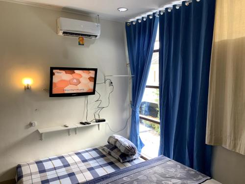 a bedroom with a bed and a tv on the wall at Awana Dream 4 bedrooms house , 5min to Alun Alun, Kraton, Malioboro bdc in Yogyakarta