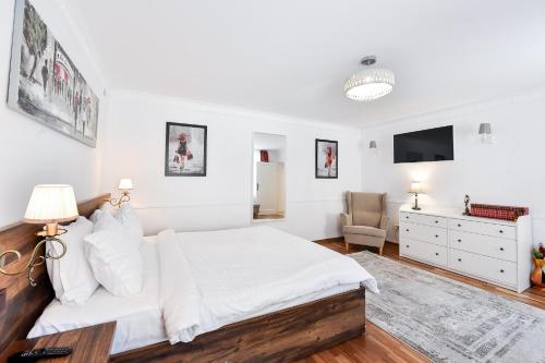 a white bedroom with a bed and a tv at FiveRooms in Braşov