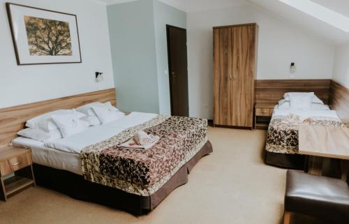 a hotel room with two beds and a chair at Hotel Dębowe Wzgórze Wellness & Spa in Jarnołtówek
