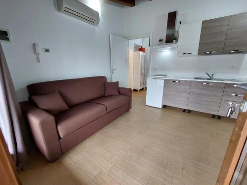 a living room with a brown couch and a kitchen at Pizzocolo resort fasano in Gardone Riviera