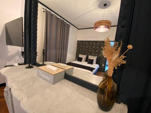 - un salon avec un canapé et un vase fleuri dans l'établissement Le manoir des rêves, bulle de confort et de sérénité, proche clinique d'Europe, Parking privé gratuit, à Rouen