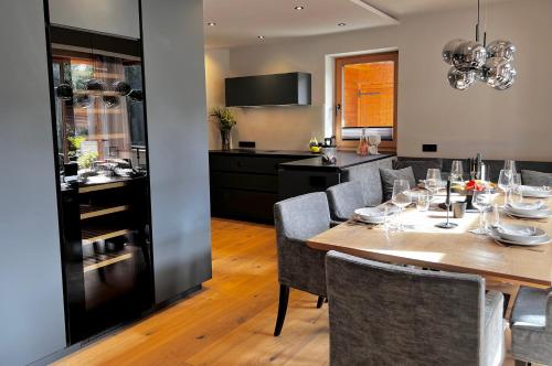 uma sala de jantar com mesa e cadeiras e uma cozinha em BOUTIQUE KAISERLODGE mit privater SAUNA & WHIRLPOOL by Belle Stay em Kitzbühel