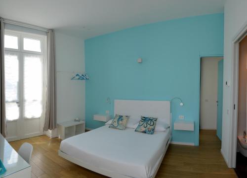 a bedroom with a white bed with a blue wall at Ca del Lac Rooms in Castro