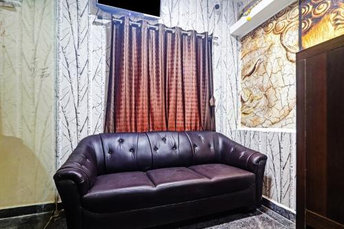 a brown leather couch in a room with a curtain at Super Hotel O Alwal Residency in Hyderabad