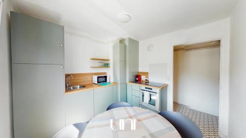 une petite cuisine avec des armoires blanches et une table dans l'établissement Appartement cosy d'Auge, à Caen